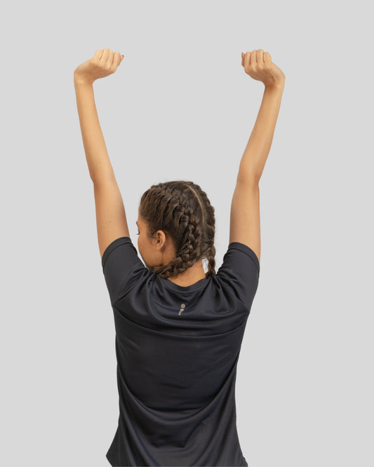 Person stretching with arms raised against a light gray background