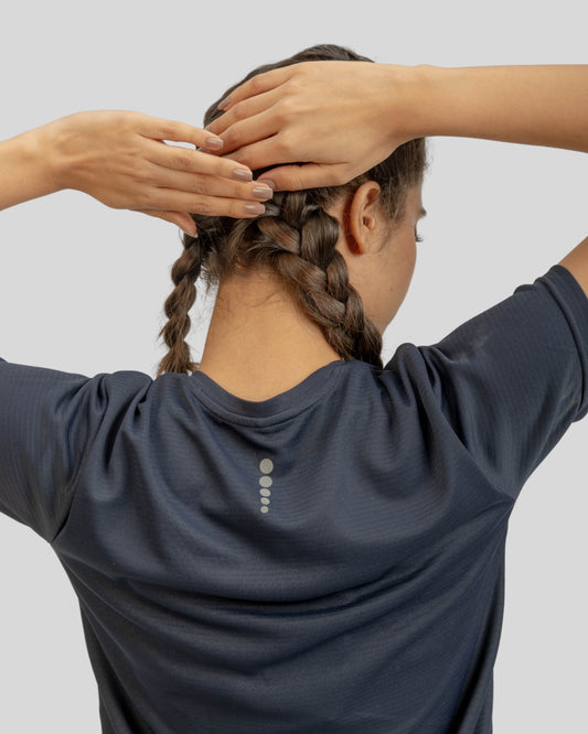 Person styling their braided hair with hands on a plain background
