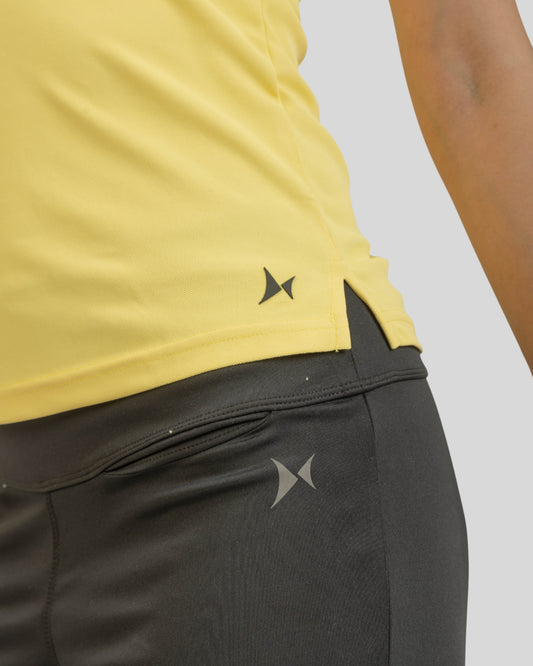 Person wearing a yellow top and black pants with a brand logo on a light gray background
