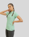 Woman wearing a light green polo shirt and black pants on a gray background