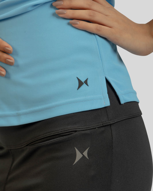 Close-up of a person wearing a blue shirt and black pants with a logo on a light gray background
