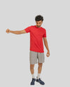 Man wearing a red t-shirt and gray shorts on a light gray background