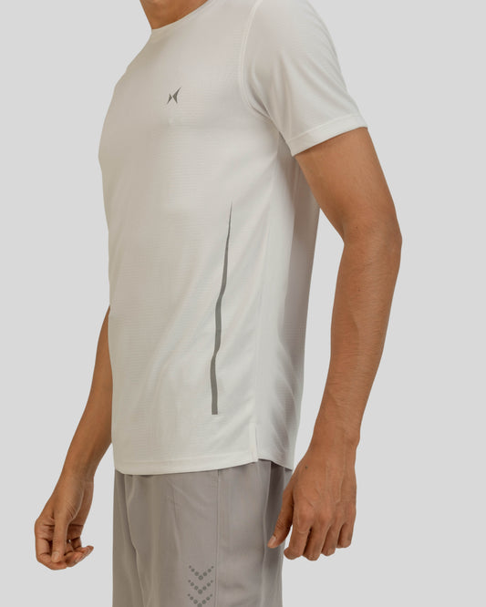 Person wearing a light gray t-shirt with a logo on a plain background