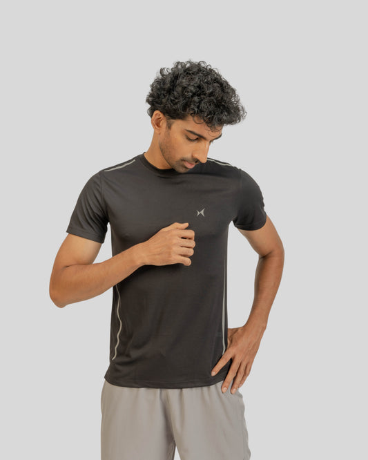 Man wearing a black athletic shirt with a logo on a gray background
