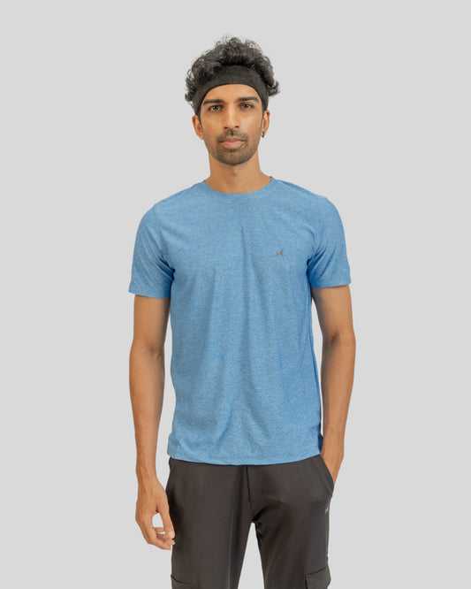 Man wearing a blue t-shirt and dark pants on a gray background