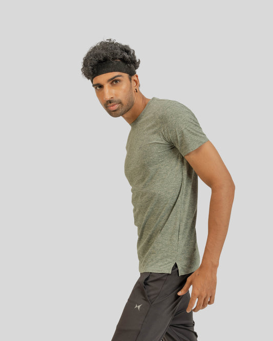 Man wearing a green t-shirt and dark pants on a light gray background