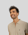 Man wearing a beige polo shirt with a small logo on a light gray background