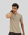 Man wearing a beige polo shirt with a small logo on a light gray background