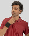 Man wearing a red polo shirt with a small logo on a plain background