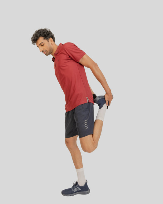 Man in athletic wear stretching on a plain background