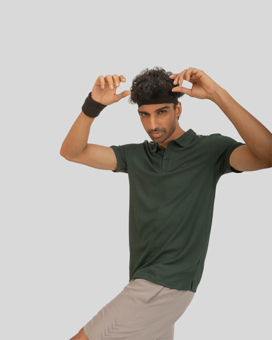 Man wearing a green polo shirt and beige shorts on a light gray background