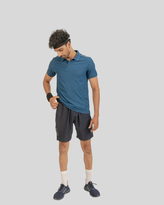 Man wearing a blue polo shirt and black shorts on a gray background
