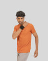 Man wearing an orange t-shirt with a black logo on a light gray background