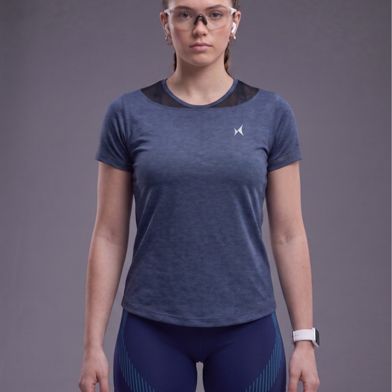 Woman wearing a blue athletic outfit with a logo on a gray background