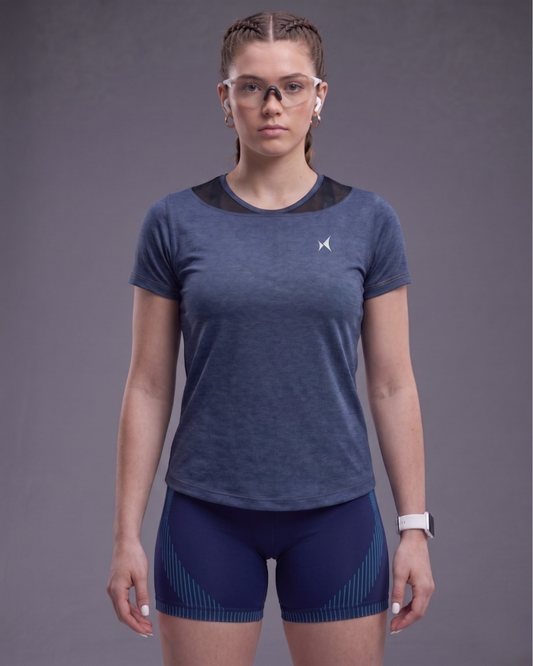 Woman wearing a blue athletic outfit with a logo on a gray background