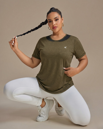 Woman wearing a green athletic shirt with a logo on a beige background