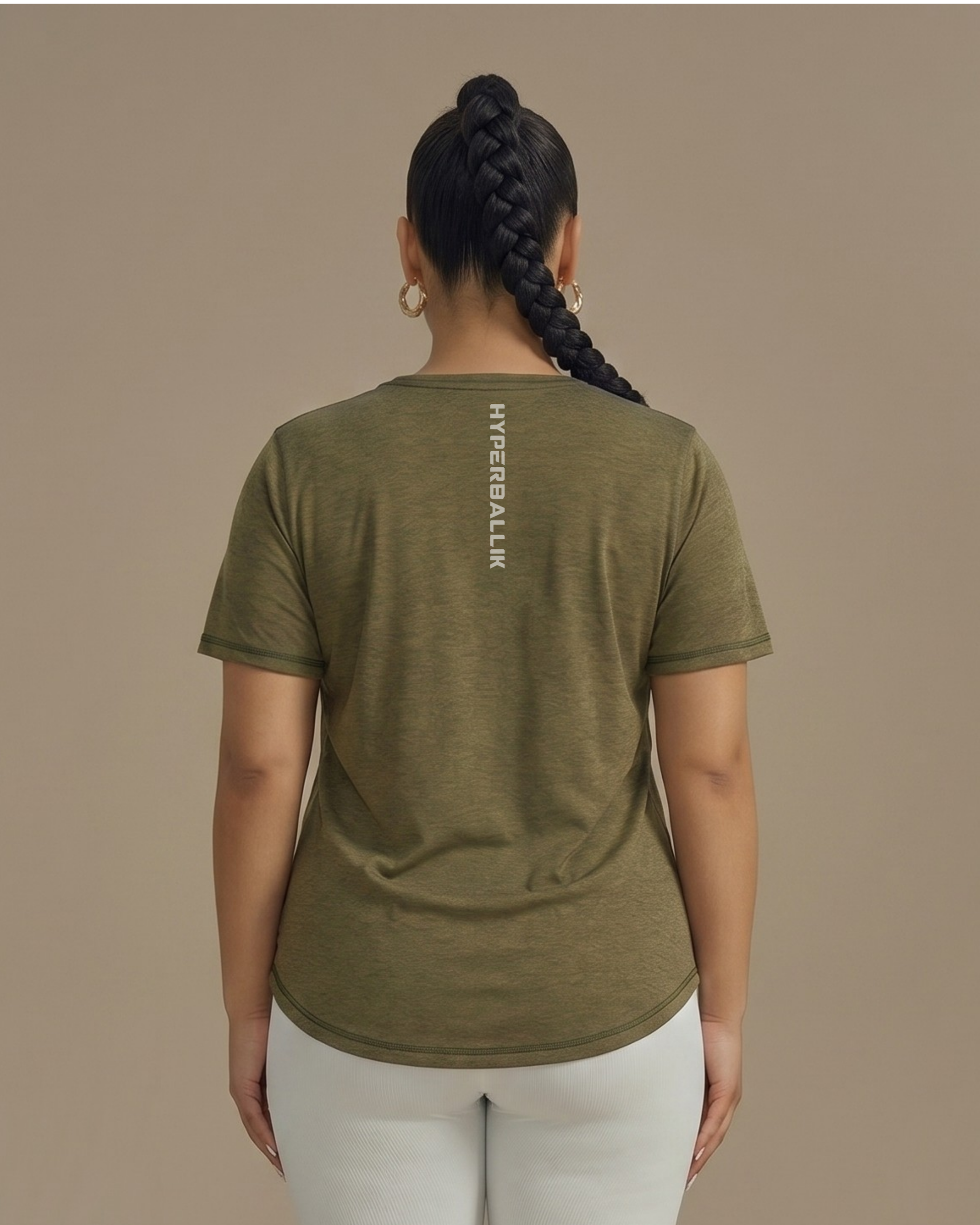 Person wearing an olive green t-shirt with a brand logo on the back against a beige background