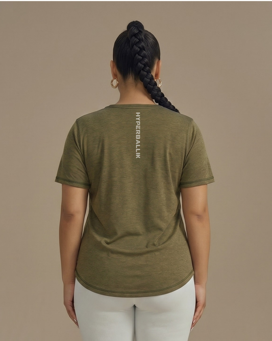 Person wearing an olive green t-shirt with a brand logo on the back against a beige background