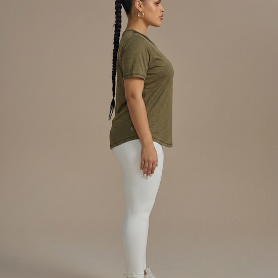 Woman wearing an olive green t-shirt and white pants against a beige background