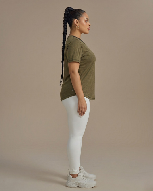 Woman wearing an olive green t-shirt and white pants against a beige background