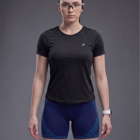 Person wearing a black athletic shirt and blue shorts on a gray background