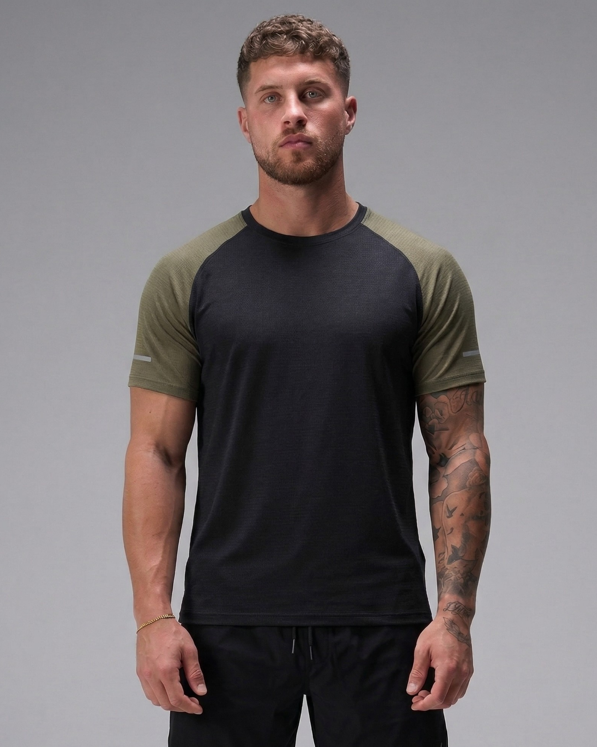 Man wearing a black and green t-shirt against a gray background