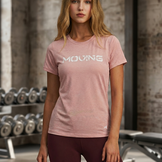Woman wearing a pink t-shirt with 'MOVING' text in a gym setting