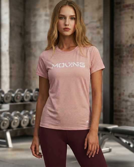 Woman wearing a pink t-shirt with 'MOVING' text in a gym setting