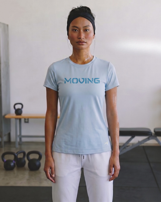 Person wearing a light blue 'MOVING' t-shirt in a gym setting