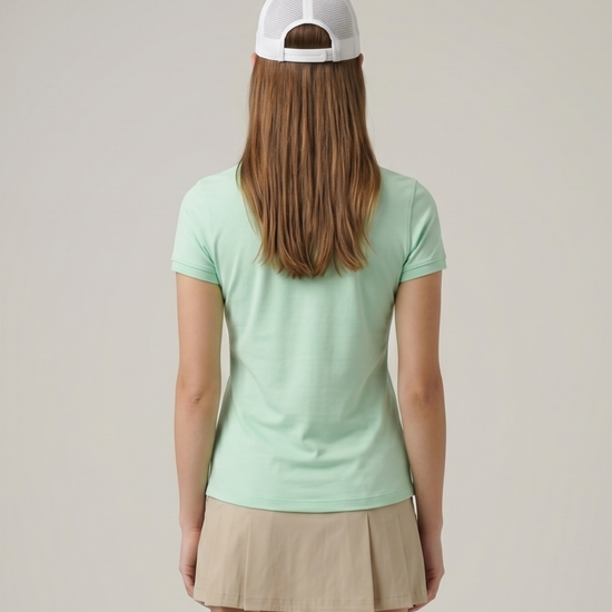Person wearing a light green t-shirt and beige skirt with a white cap on a plain background