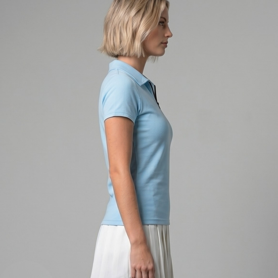 Woman wearing a light blue polo shirt and white skirt on a gray background
