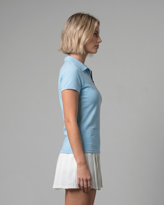 Woman wearing a light blue polo shirt and white skirt on a gray background