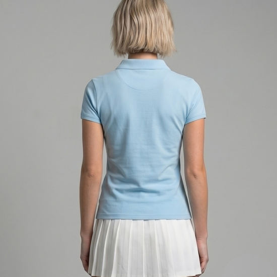 Person wearing a light blue polo shirt and white pleated skirt on a gray background