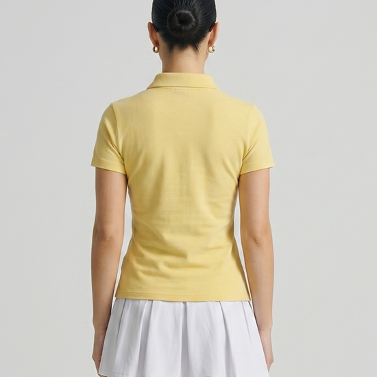 Person wearing a yellow polo shirt and white skirt on a plain background