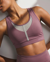 Person wearing a mauve sports bra and leggings with a visible brand logo.