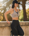 Woman in athletic wear leaning against a wall outdoors