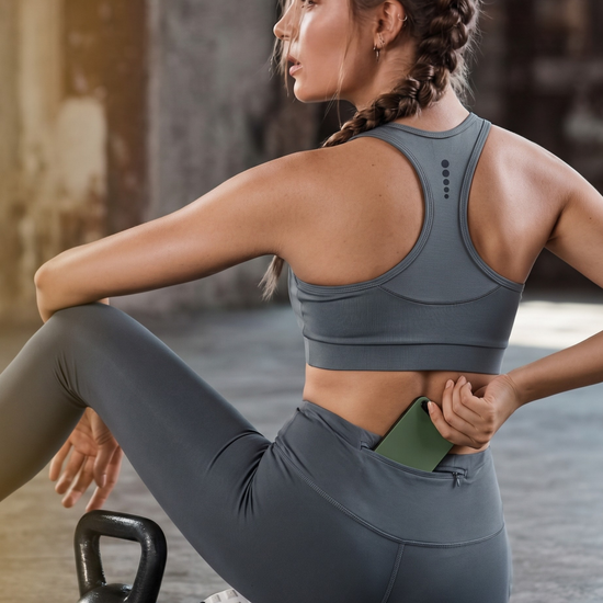 Woman in gray athletic wear stretching with a kettlebell on a wooden floor.