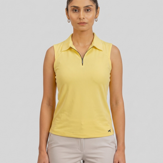 Woman wearing a yellow sleeveless polo shirt and beige shorts on a gray background