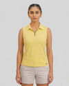 Woman wearing a yellow sleeveless polo shirt and beige shorts on a gray background