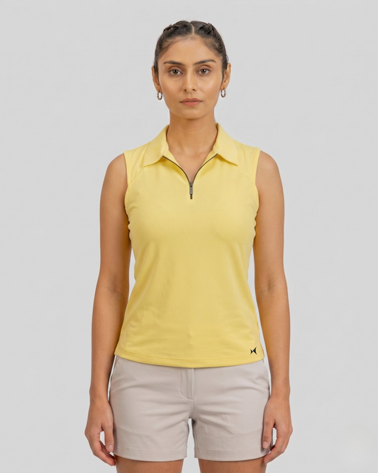 Woman wearing a yellow sleeveless polo shirt and beige shorts on a gray background