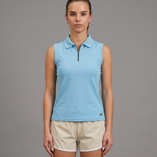 Woman wearing a light blue sleeveless polo shirt and beige shorts on a gray background