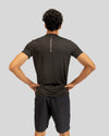 Person wearing a black athletic outfit with visible branding on a gray background