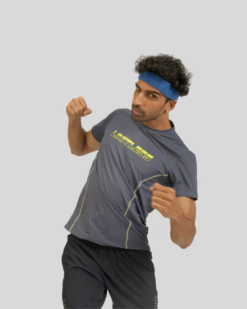 Man wearing a gray athletic shirt with yellow text and black shorts on a light gray background