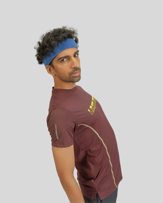 Man wearing a maroon athletic shirt with a logo on a light gray background