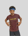 Man wearing a maroon t-shirt with 'LIMITLESS' text, blue headband, and dark shorts on a light gray background