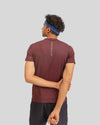 Person wearing a maroon athletic shirt with a visible brand logo on the back, standing against a plain background.