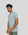 Man wearing a light blue t-shirt and green shorts on a plain background