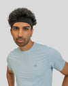 Man wearing a light blue t-shirt with a logo on a plain background