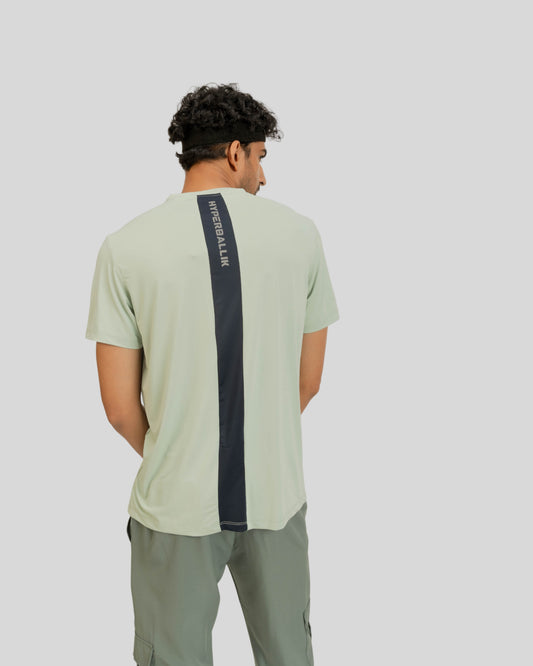 Person wearing a light green t-shirt with a dark blue stripe on a plain background