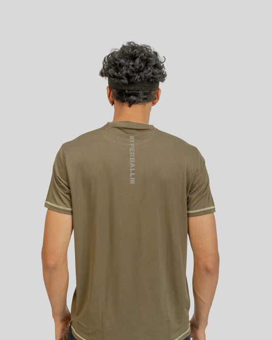 Person wearing a brown t-shirt with a brand logo on the back against a light gray background